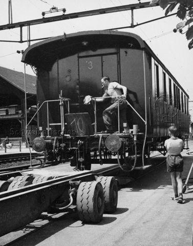 "Park im Grüene", Rüschlikon, Transport eines alten Zugwaggons - Wagen "wird auf den geleerten Schlepper geladen, der zuvor die Schienen transportiert hatte"; um 1960