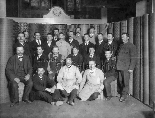 Linoleumleger, inmitten von Linoleumrollen posierend