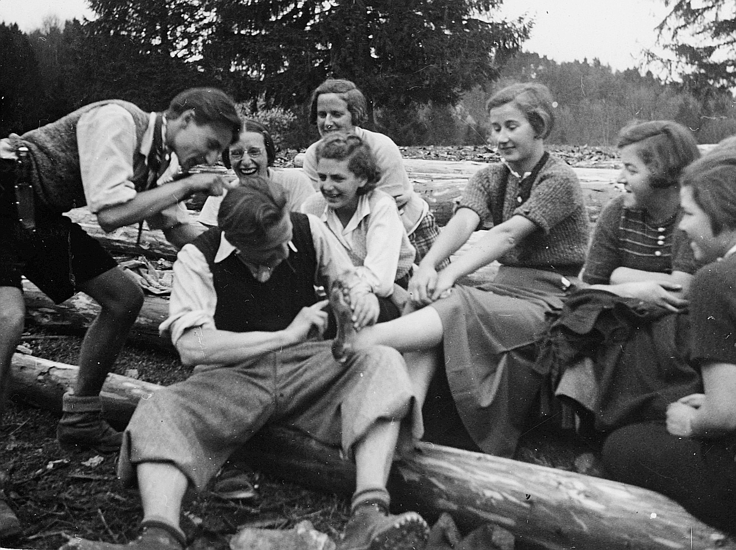 Eine Jurafahrt der Basler Wandervögel: Wandervogel (Mann) den Fuss eines Wandervogels (Frau) berührend und andere Wandervögel zuscha