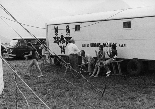 "Kinderzirkus Basilisk" - Frauen und Männer vor einem Zirkuswagen; 1970
