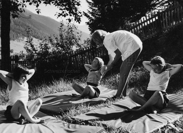 "Kinderheilstätte Davos - Asthmagymnastik" - Drei Mädchen machen draussen Übungen; um 1970
