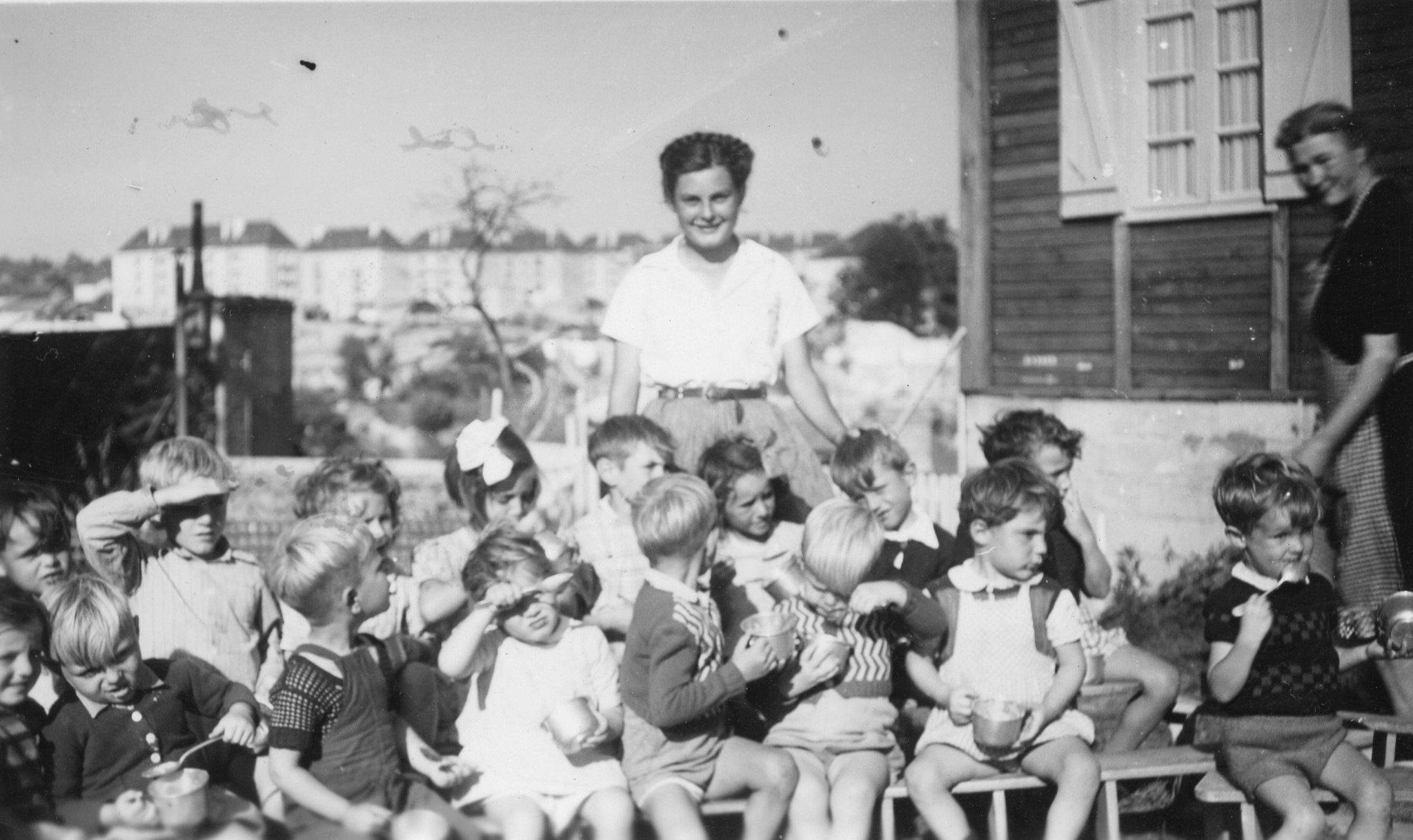 Betreuerin hinter essenden Kindern posierend