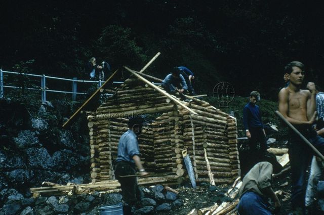 "Kinderspielplatz Rombach, Amden" - Männer und Jugendliche beim Bauen einer Blockhütte; 1971
