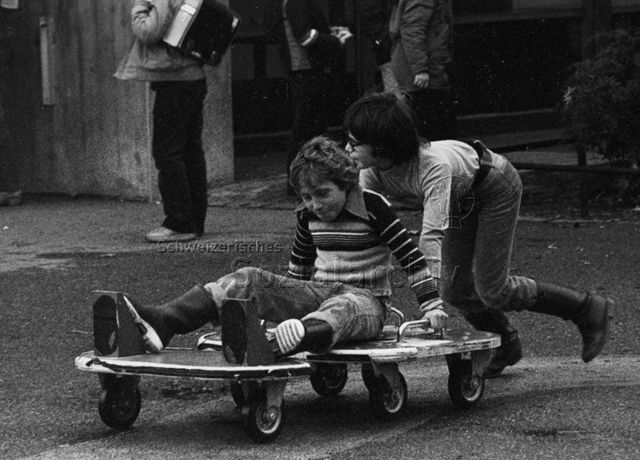 "Spielaktion, Seevogelschulhaus Basel" - Zwei Jungen beim Spielen mit fahrbahrem Untersatz; 1981