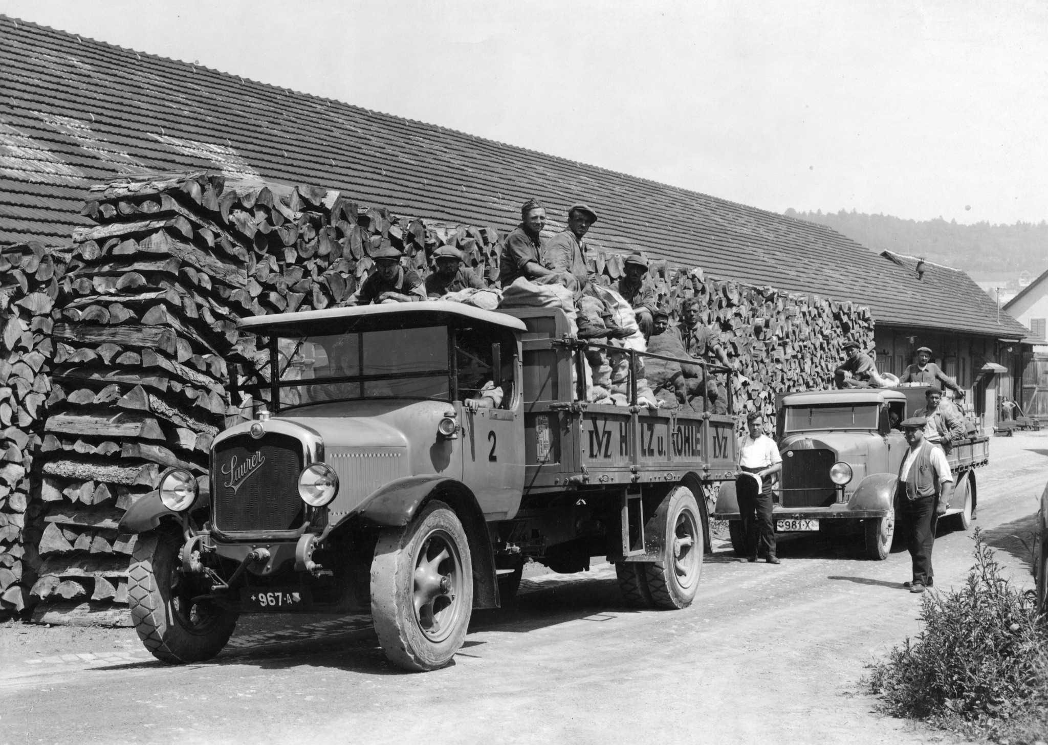 Männer auf mit Brennmaterial beladenen Lastwagen des Lebensmittelvereins Zürich im Holzlager an der Turbinenstrasse