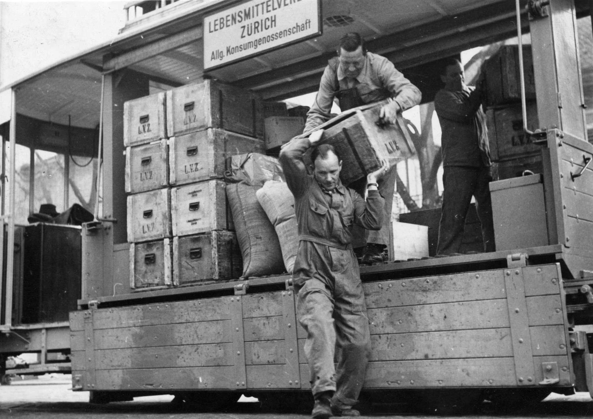 Lebensmittelverkauf des Lebensmittelverein Zürich LVZ ab Tram in Zürich: Männer laden Kisten ab