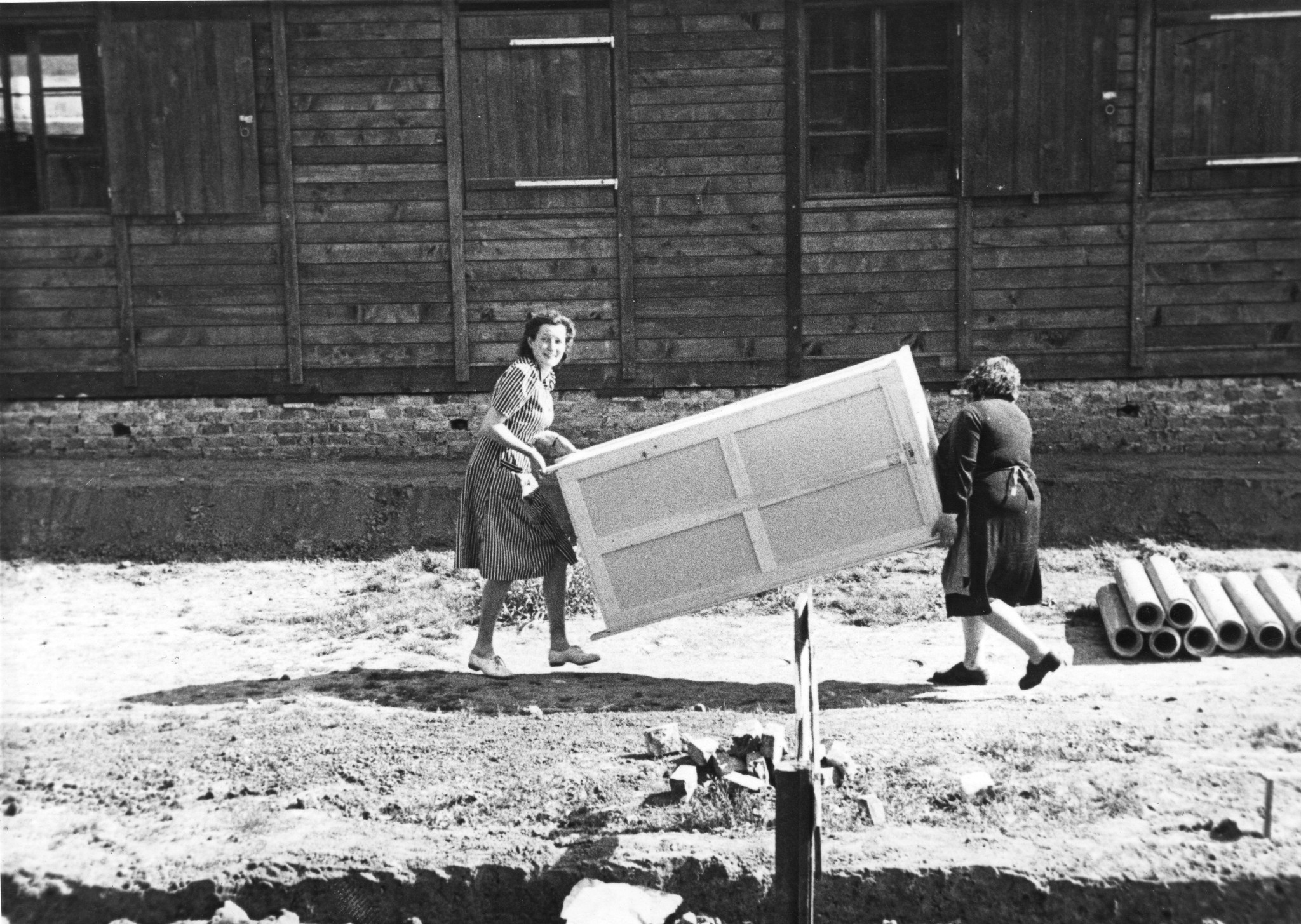 "Fives [Stadtviertel von Lille, Nord-Pas-de-Calais] Möbelverteilung", zwei Frauen tragen einen Schrank, vermutlich vor dem SAH-Sozialzentrum, um 1946