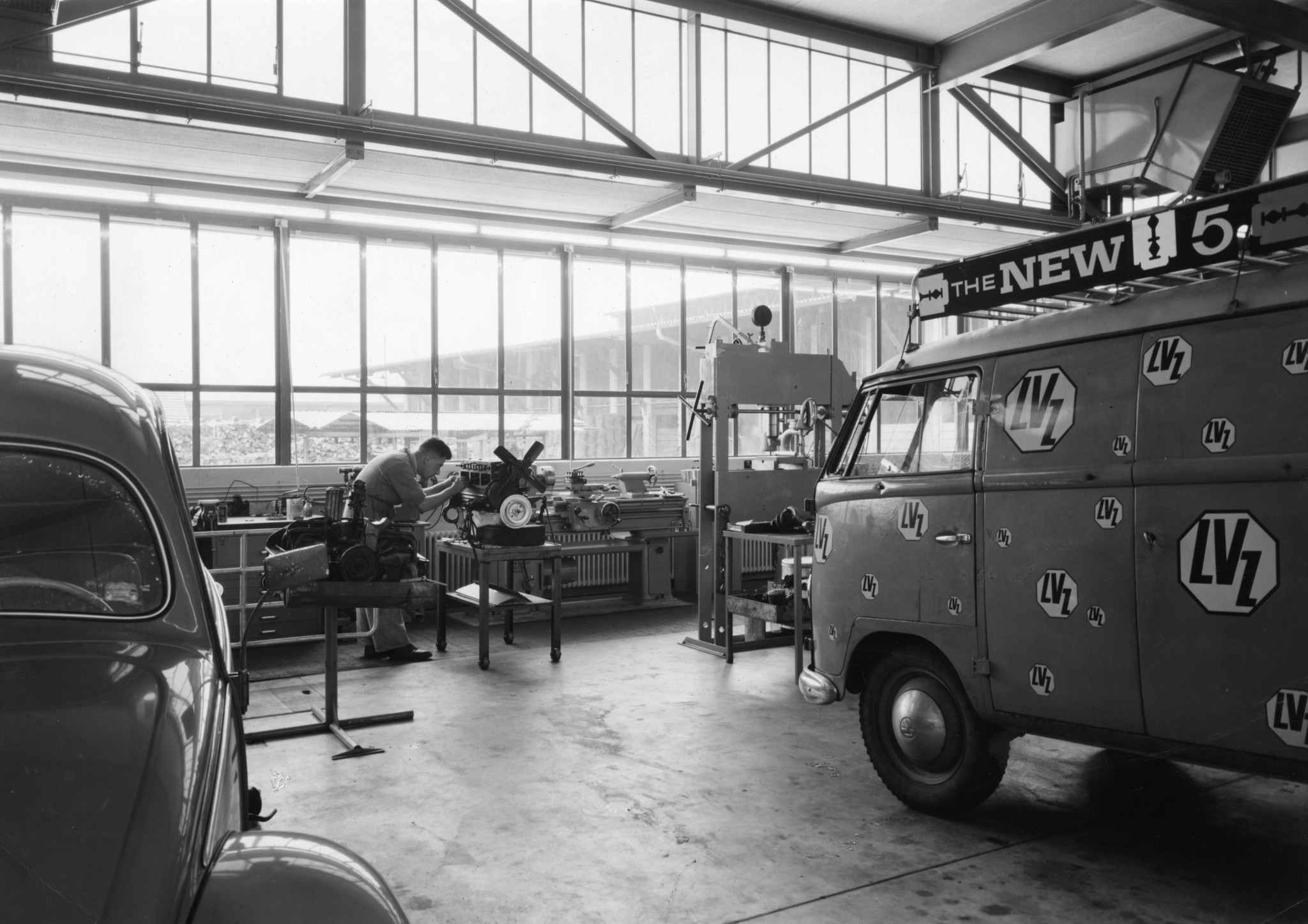 Lieferwagen des Lebensmittelvereins Zürich in einer Werkstätte, Mechaniker beim Arbeiten an einem Motor