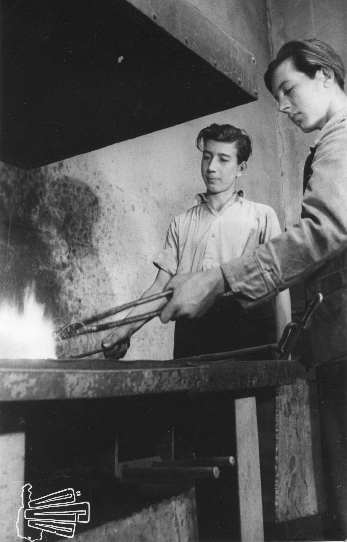 "Österreichische Lehrwerkstätten. In der Schmiede: Der Lehrling muss sein Werkzeug selber richten können", Auszubildende bei der Arbeit, Wien, um 1950
