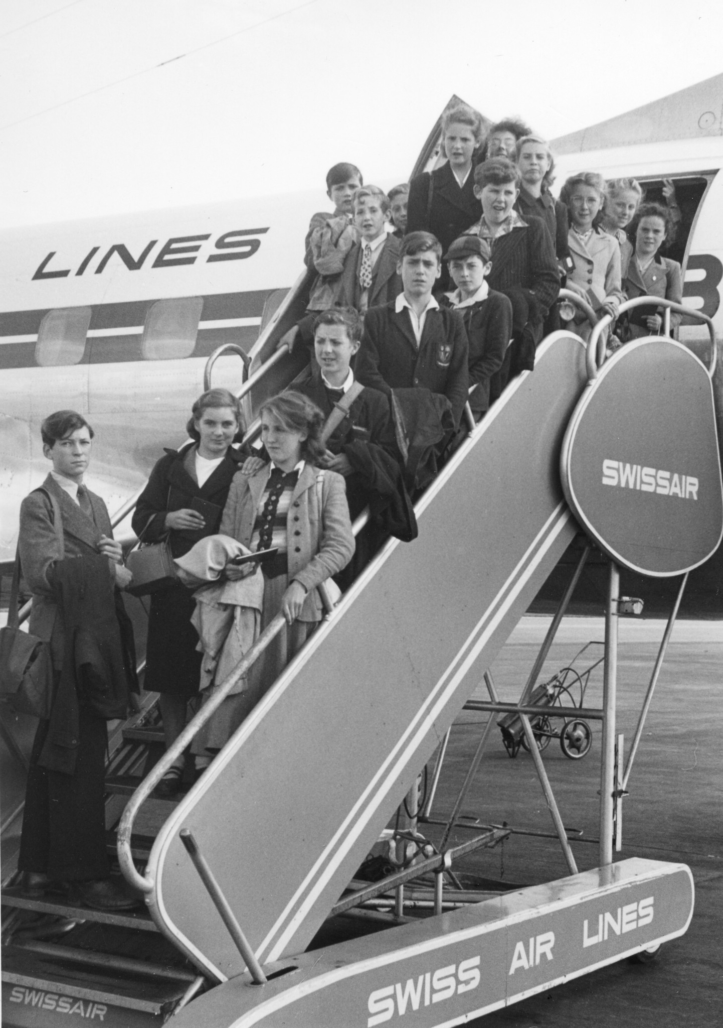 Kinder stehen auf der Ausstiegstreppe eines Flugzeuges der Swissair