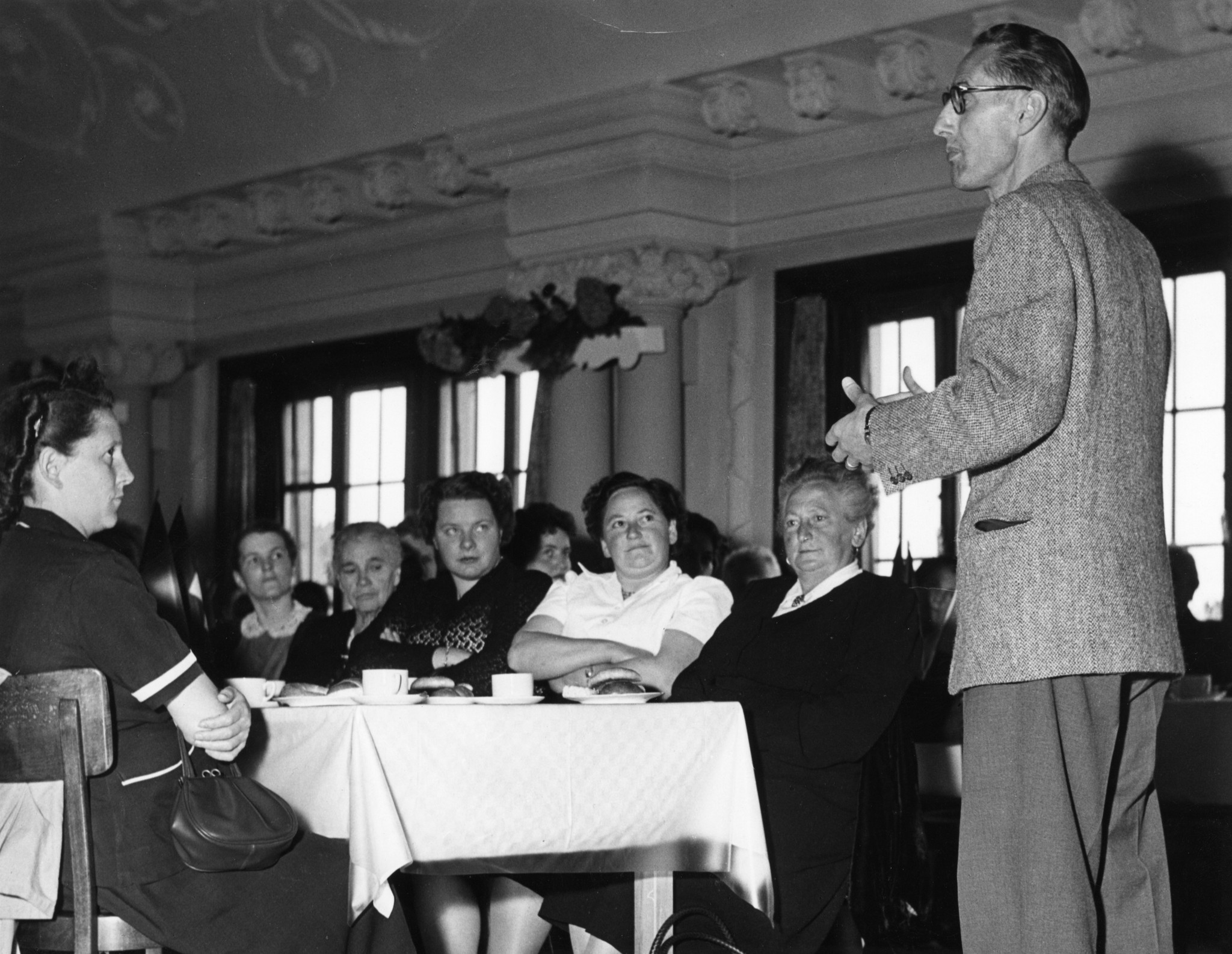Mitarbeiterversammlung 1940er / 50er Jahre: Mann spricht zu einer Gruppe Frauen