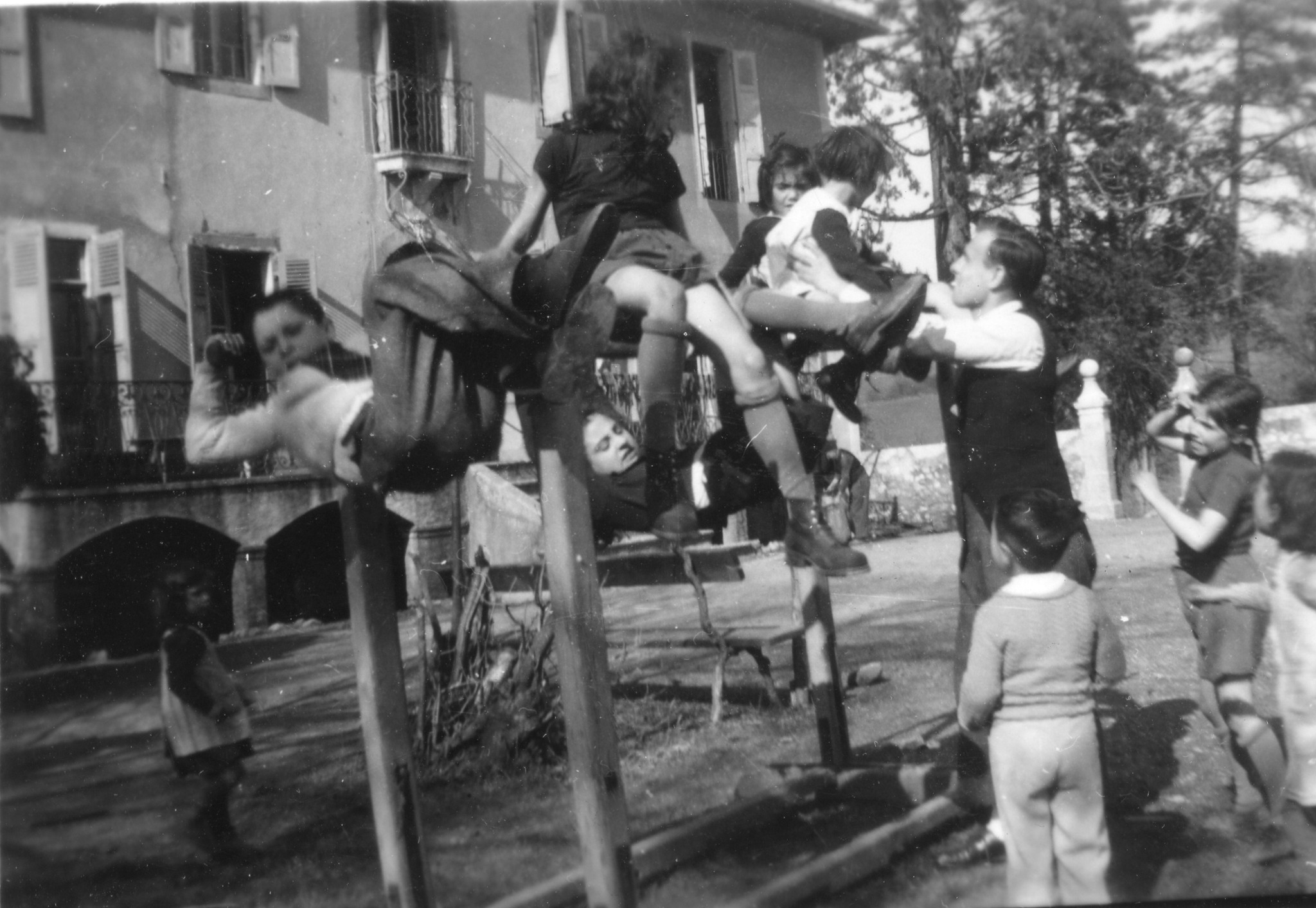 Von einem Betreuer beaufsichtigt, turnen Kinder auf einem Barren