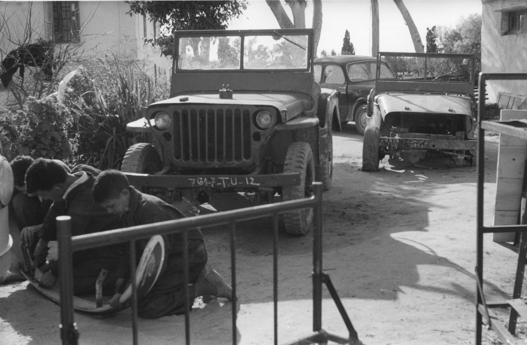 Drei Knaben arbeiten an der Stossstange eines Autos