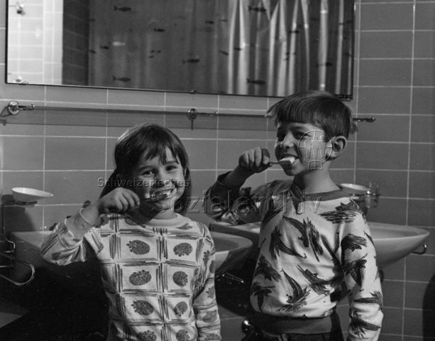 Ein Mädchen und ein Junge beim Zähneputzen im Badezimmer; um 1975