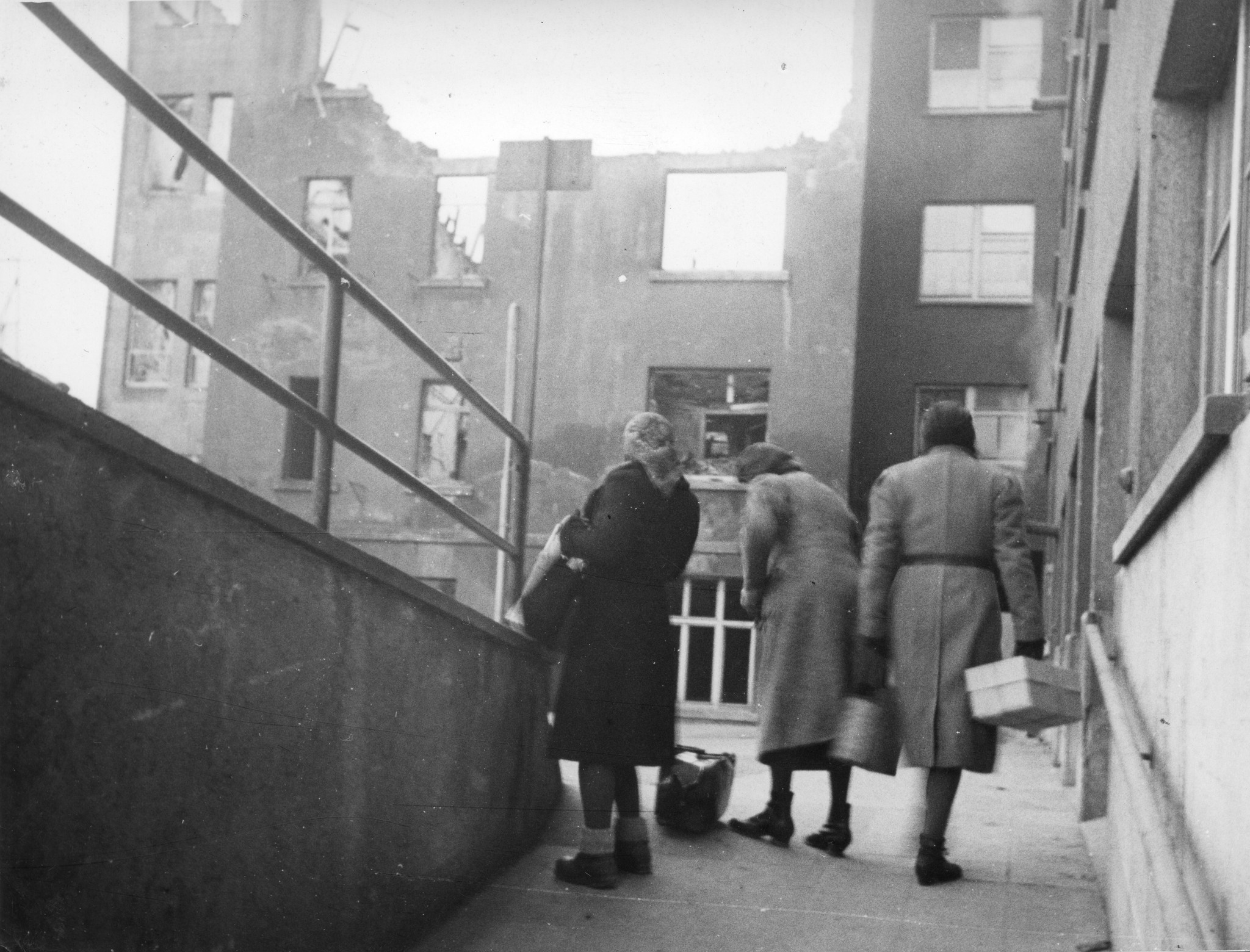 "Colis Suisse, Verteilungsstellen"; Drei Frauen stehen mit Tüten vor einem zerbombten Gebäude