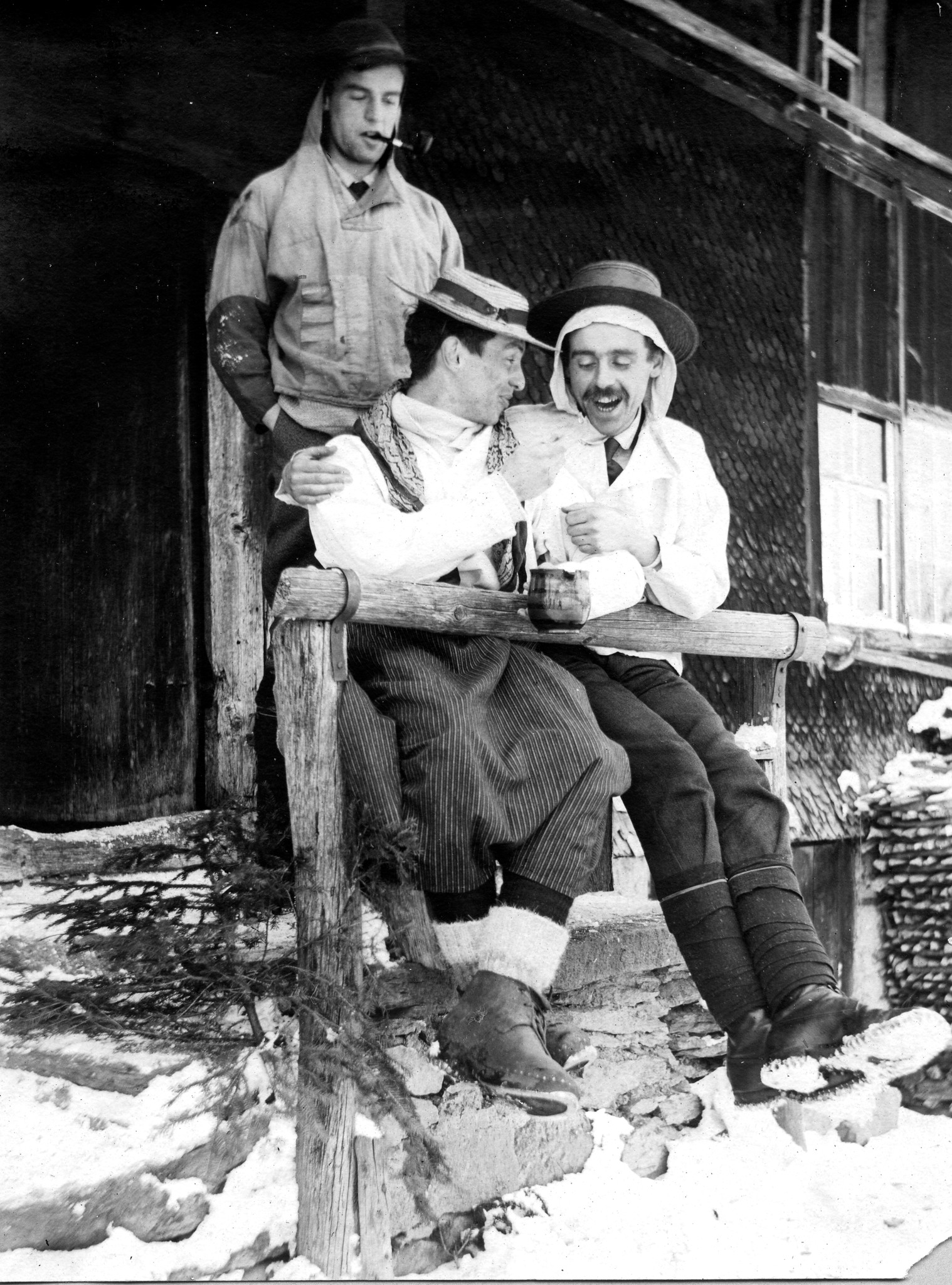 Skilager Obstalden: Zwei lachende Wandervögel vor dem Skilagerhaus, ein dritter Wandervogel eine Tabakpfeife rauchend (1910/11)