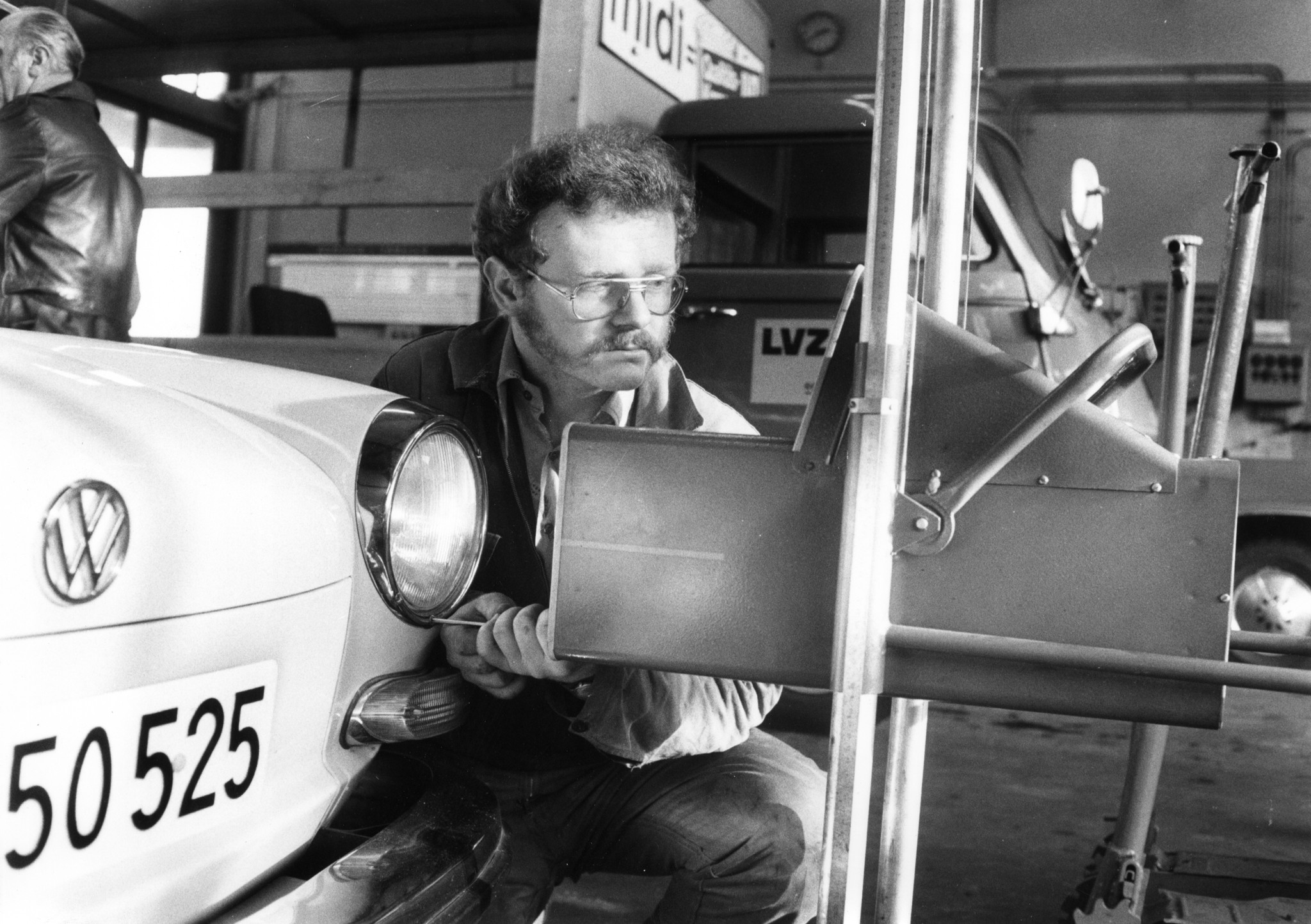 Automechaniker beim Schrauben zum Einstellen des linken Scheinwerfers eines Autos