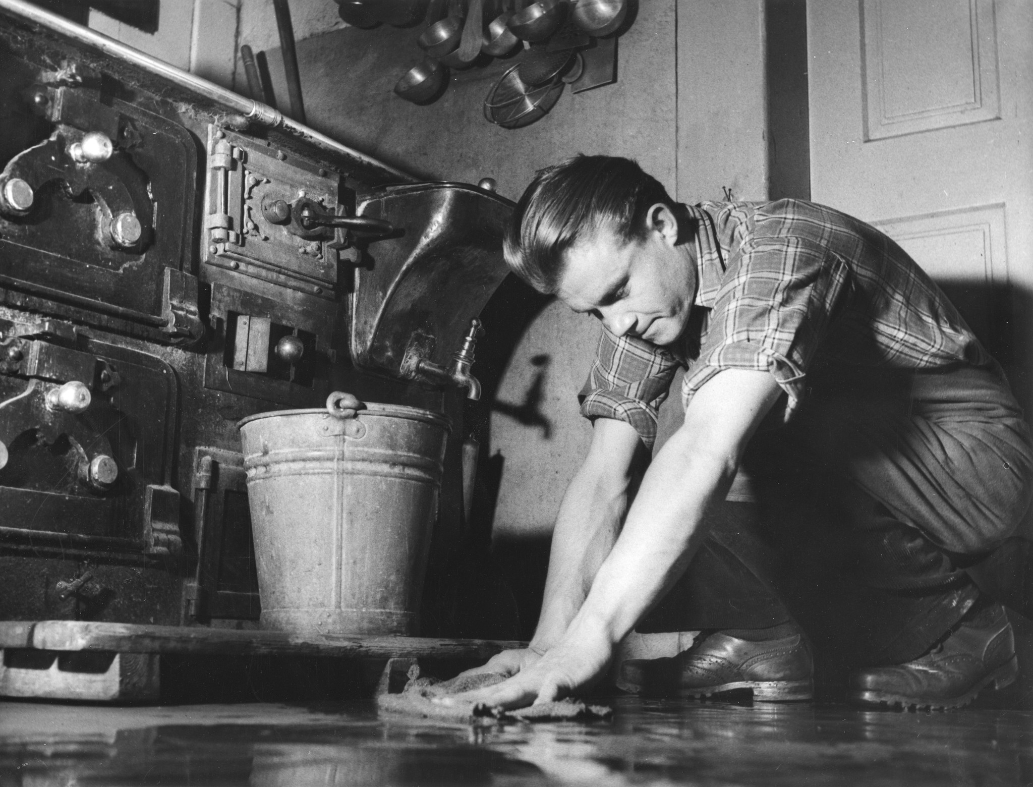 Erholungsaktion für jugendliche deutsche Flüchtlinge im Ferienhaus Lindenbühl 1952/1953; ein Jugendlicher schrubbt den Küchenboden