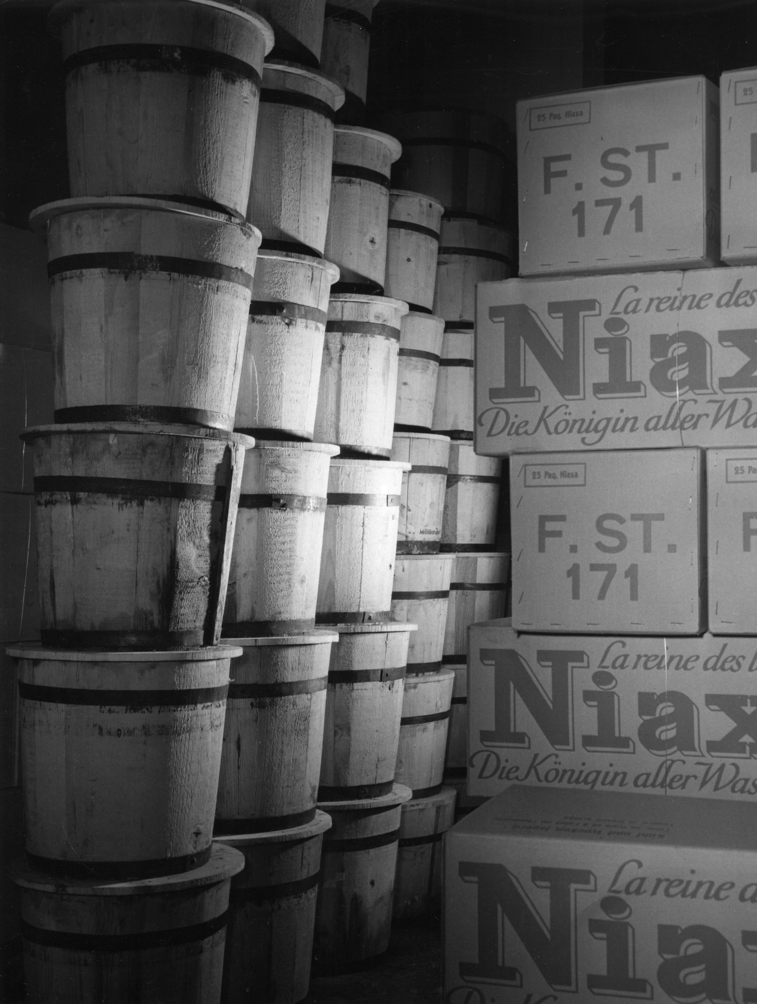 Lagerhalle: Gestappelte Kisten mit Aufdruck "Niaxa, die Königin aller Waschmittel" und Holzeimer
