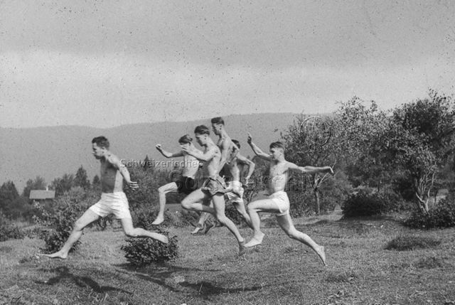 "Sport; Turnen für jedermann: Offenes Turnen im Freien" - Sechs junge Männer im Grünen, weit springend; um 1960