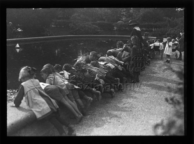 Diaserie zum Thema Kindergarten; Kinder mit zwei Betreuerinnen blicken in einen Teich; um 1930