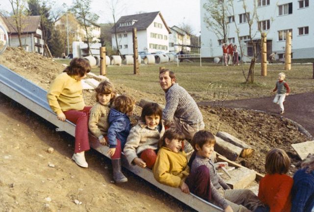 "Ebnat-Kappel, Väter bauen in Fronarbeit Kinderspielplatz" - Kinder auf der Rutschbahn, dahinter ein Vater; 1971