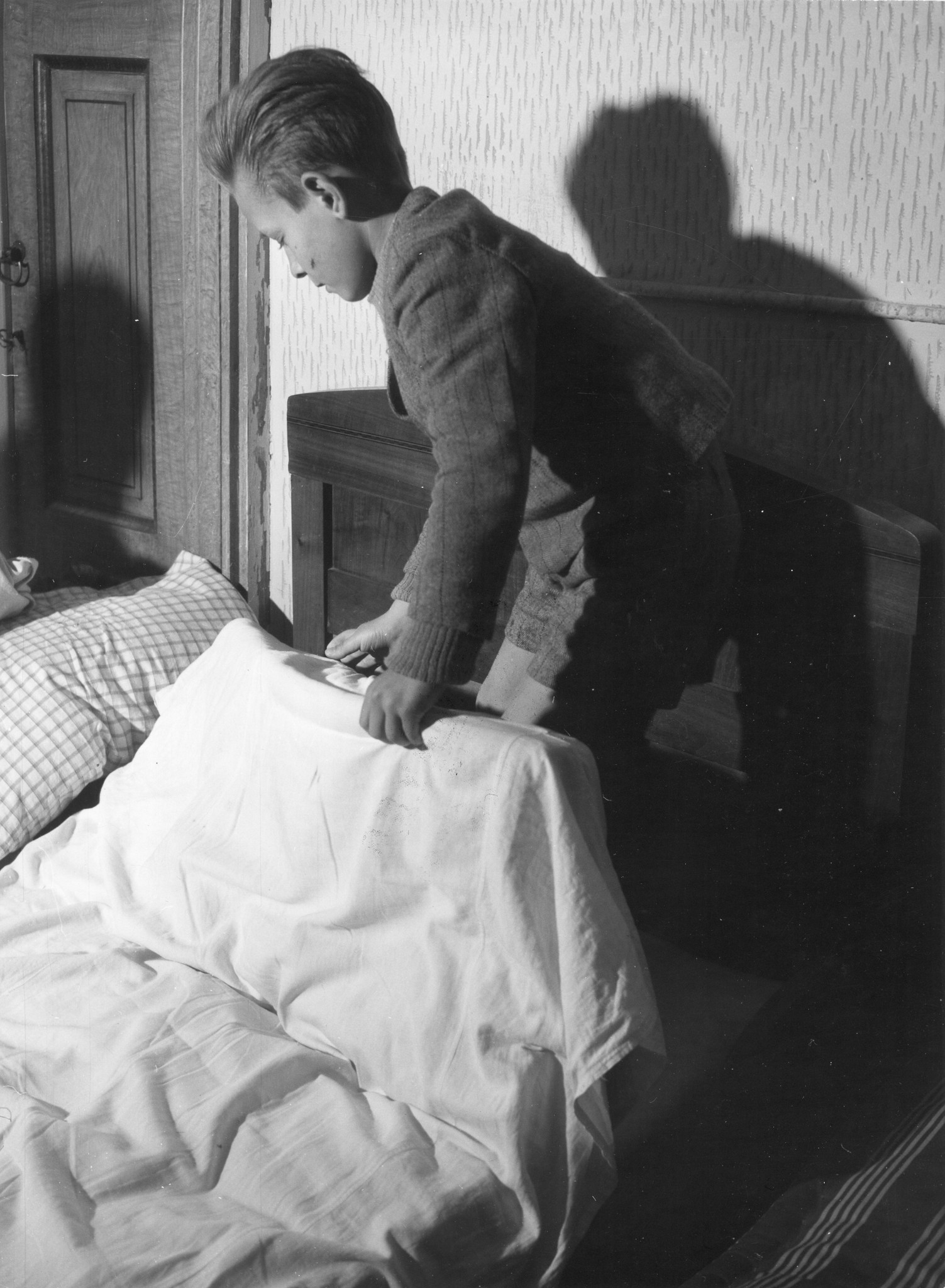 Ein Knabe bezieht sein Bett
