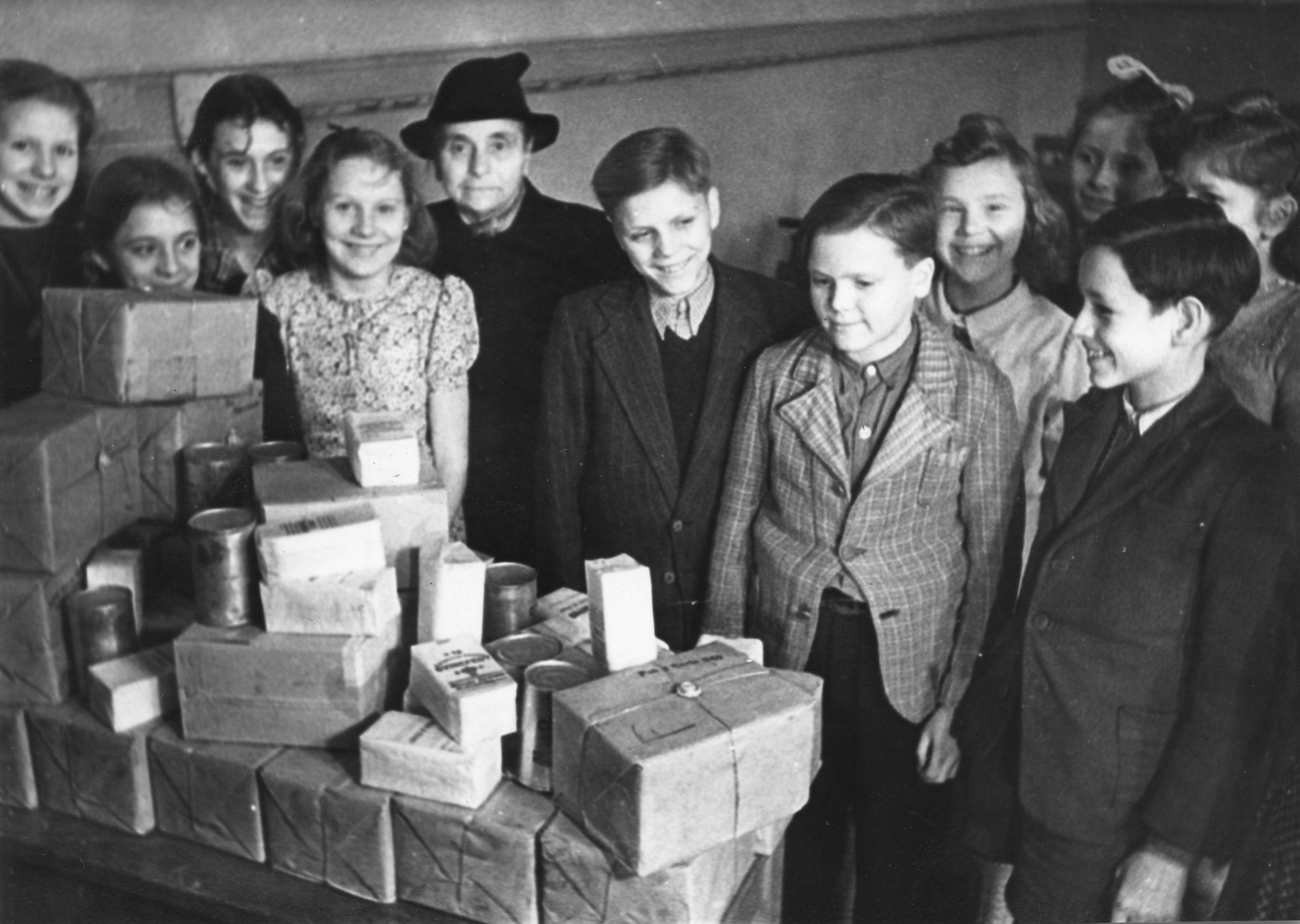 "März 1948: Verteilung von Lebensmittelpaketen am die Schüler der Gemeinschaftsschule Düsseldorf"; Kinder stehen vor einem Tisch mit Lebensmitteln