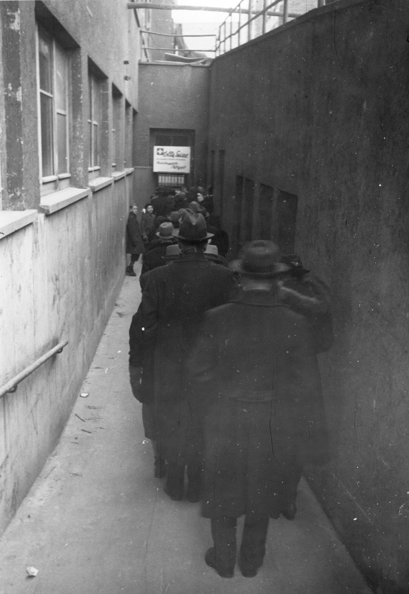 "Colis Verteilungsstelle"; Männer stehen in einer langen Schlange vor dem Verteilungszentrum an
