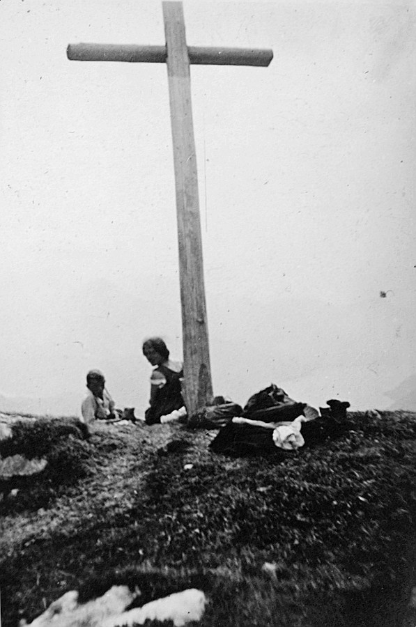 Wandervögel sitzen bei einem Holzkreuz (Holzkruzifix), vermutlich auf einem Gipfel in den Bergen (1920)