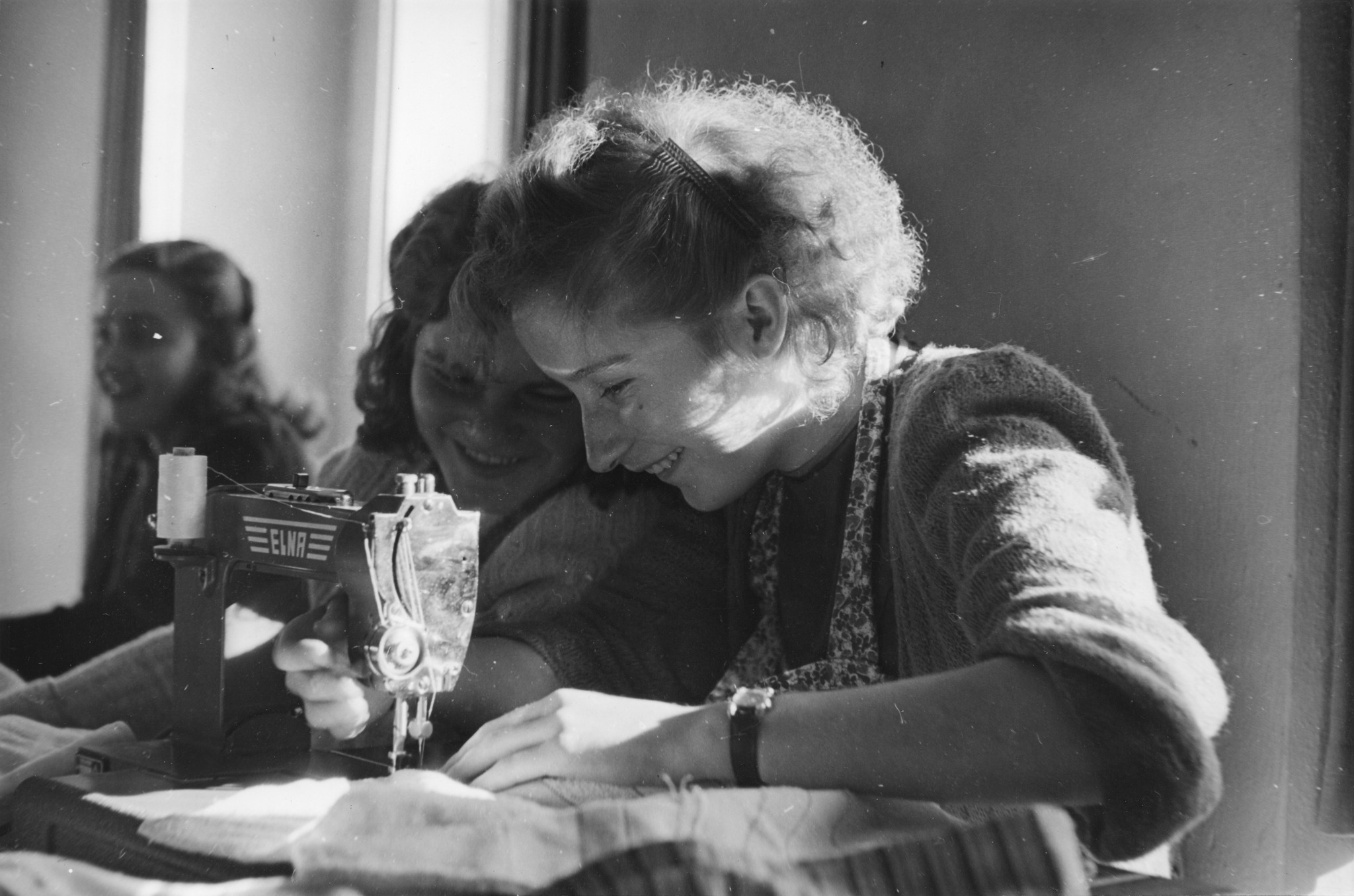 "Cavigliano - Haushaltungskurs für deutsche Flüchtlingsmädchen vom Dezember 1950 bis Februar 1951", zwei lachende Mädchen bei der Näharbeit (Nähmaschine)