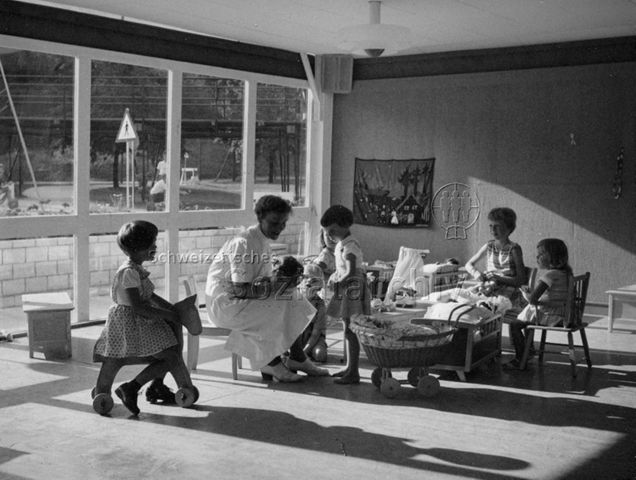 "Saffa Kinderdorf", Zürich - Kinder und Betreuerin beim Spielen mit Puppen; 1958