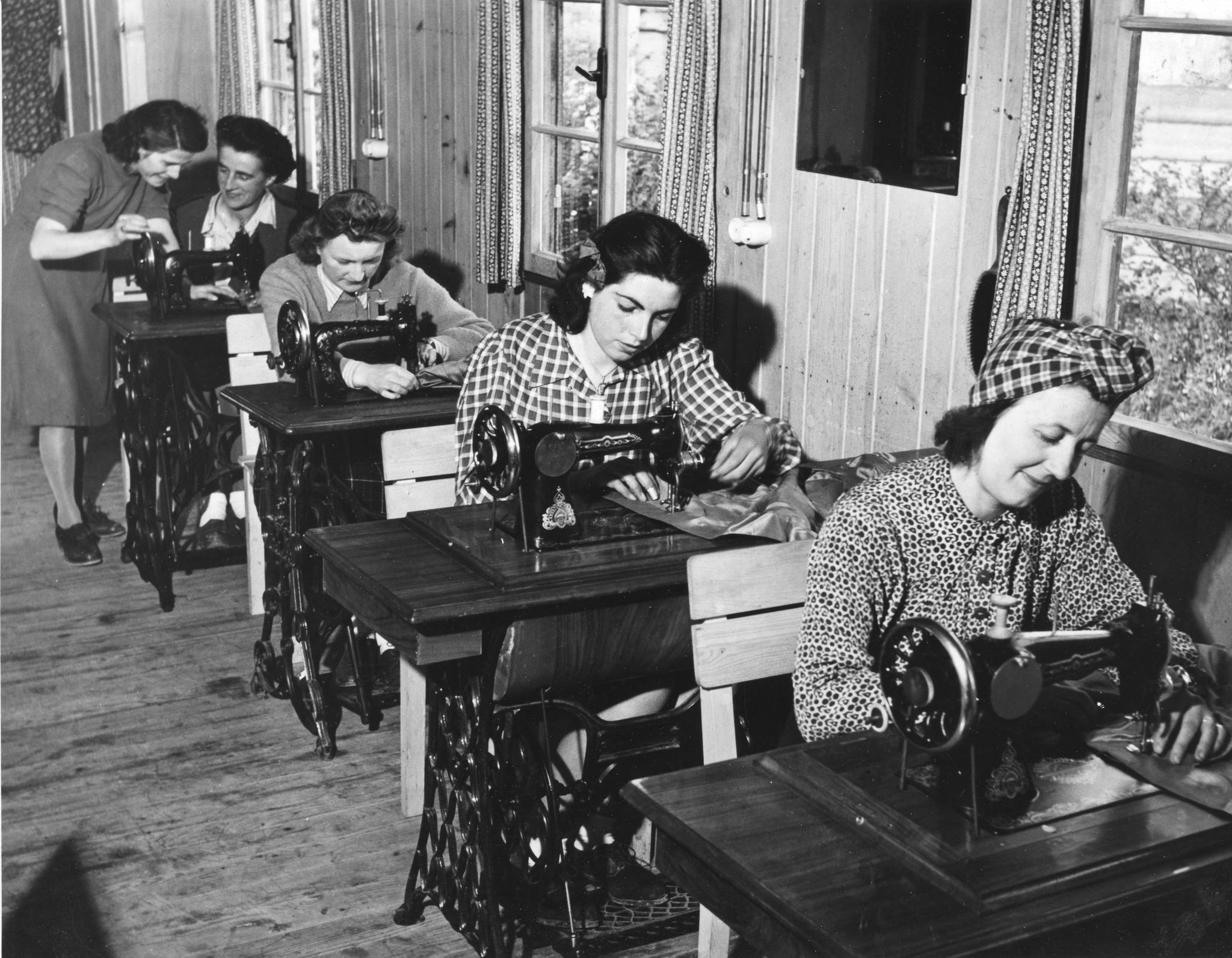 "Ouvroir". Frauen in der Nähstube des Sozialzentrums an Nähmaschinen sitzend