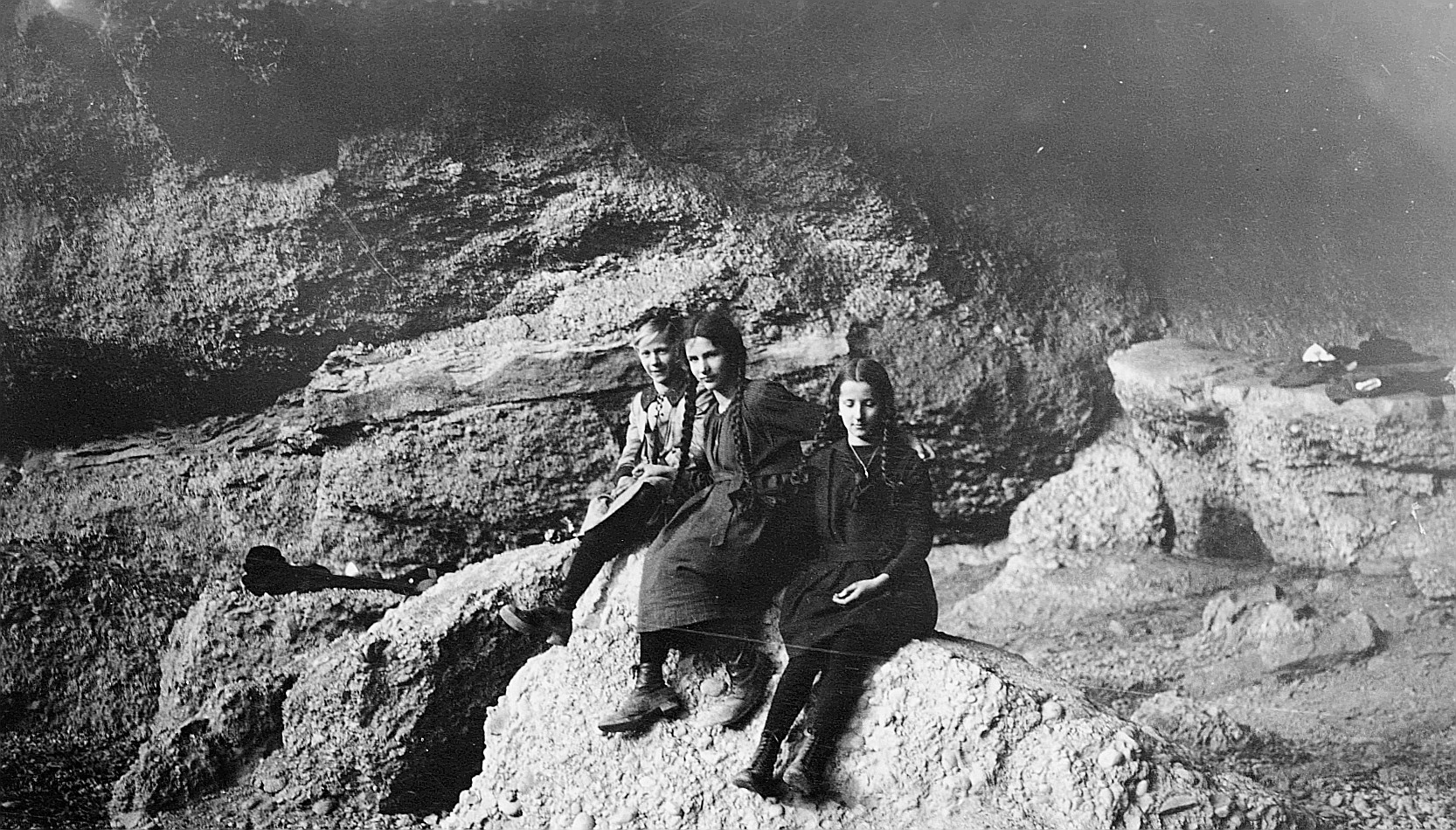 Treffahrt in der Salpeterhöhle bei Flawil der Meitli-Ortsgruppe St. Gallen-Klösterli: Drei Mädchen sitzen in der Grotte (1921)