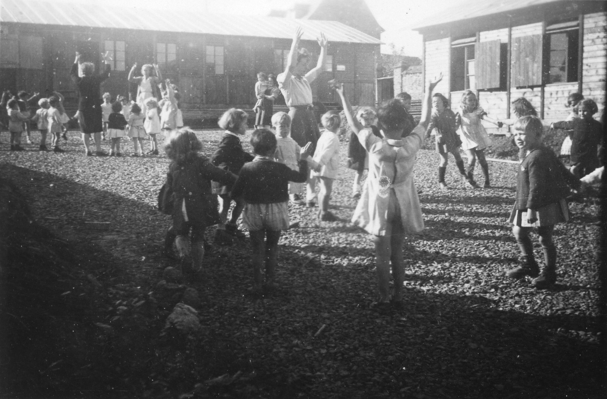 "Im Kindergarten"; Kinder und Betreuerinnen tanzen miteinander im Kreis