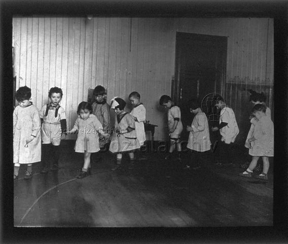 Diaserie zum Thema Kindergarten / Schulkind; Kinder gehen entlang einer auf den Boden aufgemalten Linie im Kreis; um 1930