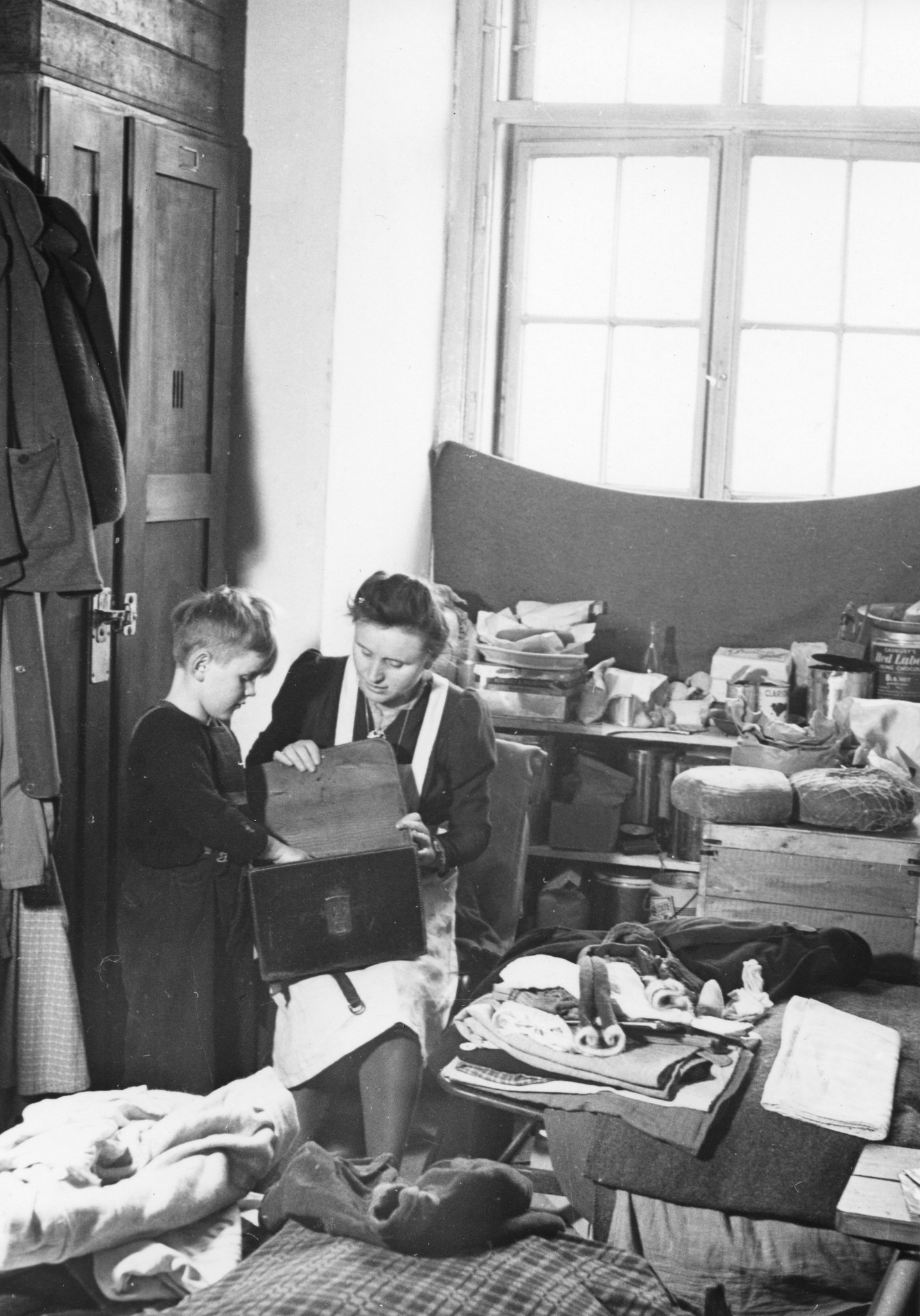 "Städtischer Flüchtlingsheim Arsenal, Wien 10, Febr. 1949", Frau und Kind bei der Auswahl von Hilfgütern