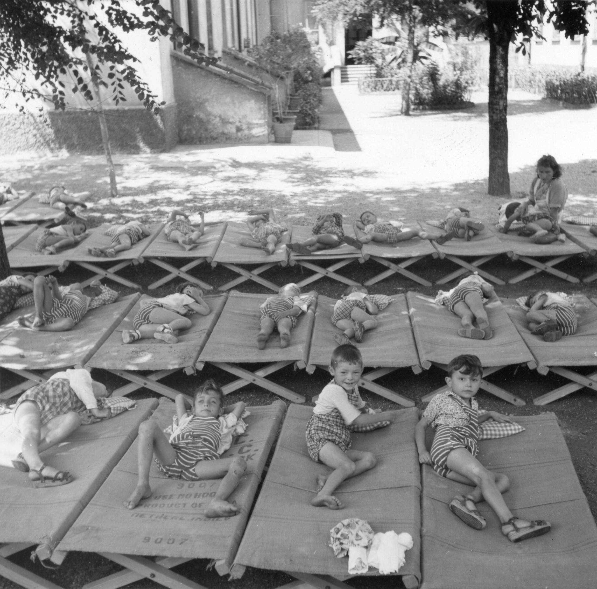 "Milano 1947. Asilo Italo-svizzero"; Kinder liegen im Garten auf Matten und machen Mittagsschlaf