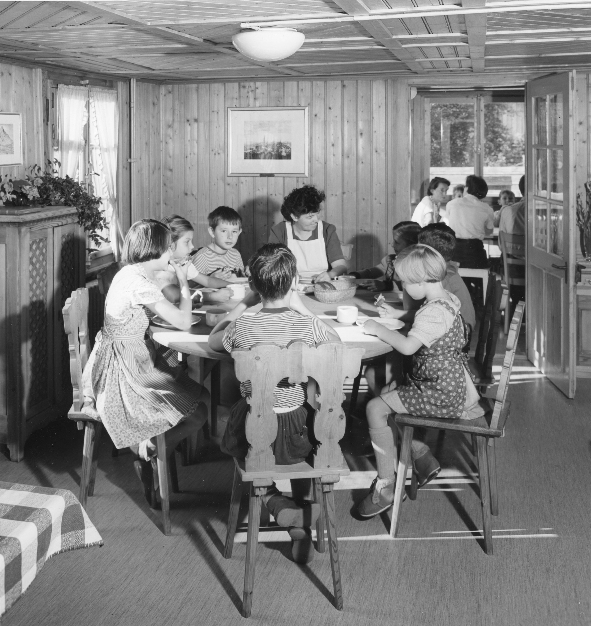 Eine Gruppe von Kindern und ihre Betreuerin nehmen im Kinderheim eine Mahlzeit zu sich