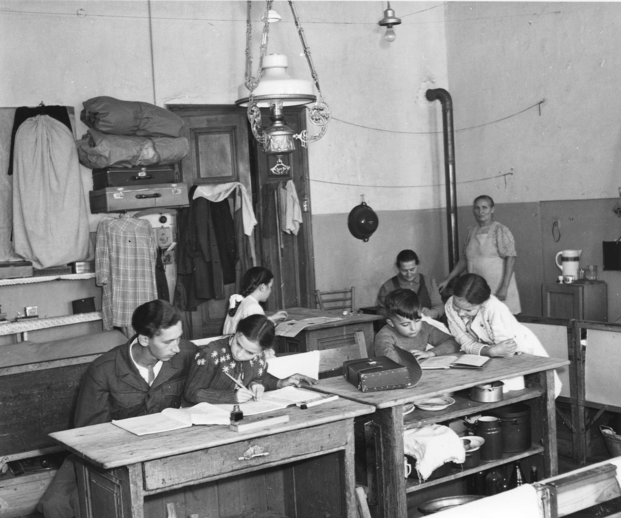 "Städtisches Flüchtlingslager Kernstockplatz, Wien XVI, Okt. 1949", Erwachsene helfen Kindern bei den Hausaufgaben