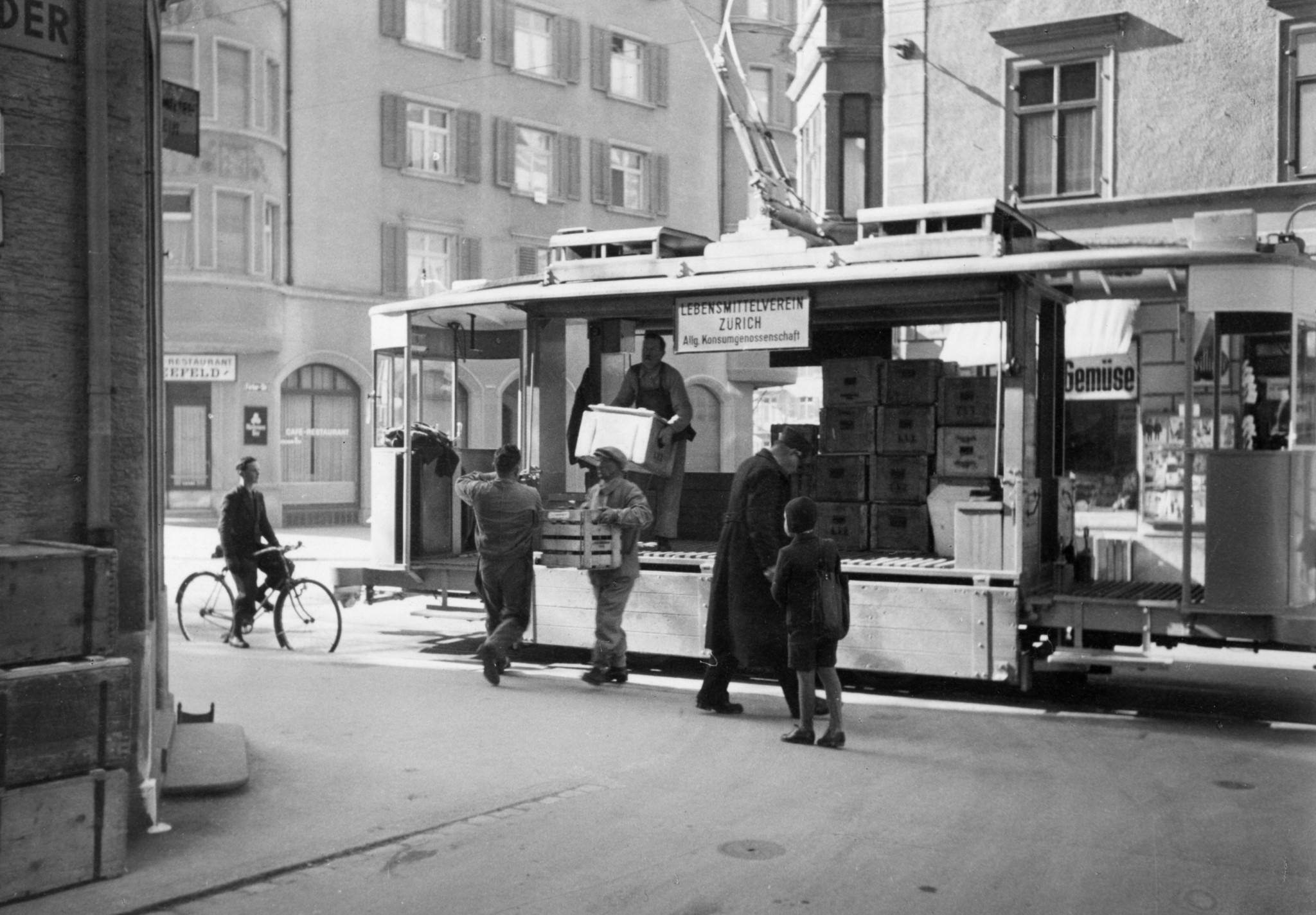 Lebensmittelverkauf des Lebensmittelverein Zürich LVZ ab Tram in Zürich: Männer laden Kisten ab
