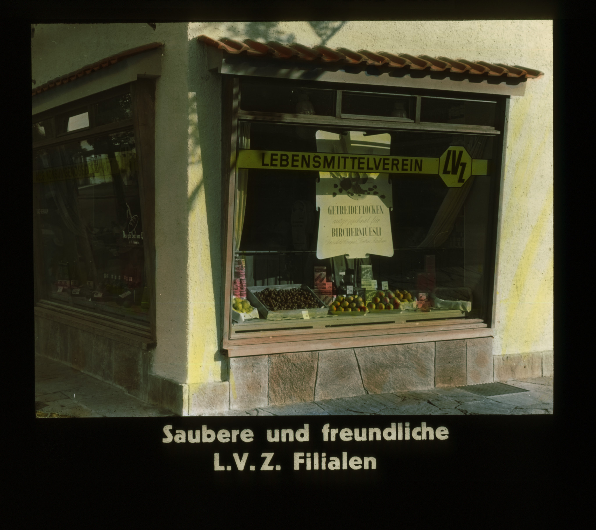 Dia: COOP/LVZ-Filiale: Schaufenster mit LVZ-Signet und Werbung für Getreideflocken und Birchermüesli, unten Text: "Saubere und freundliche L.V.Z.Filialen".
