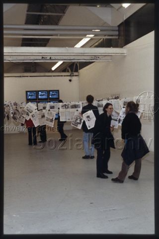 Ausstellungsansicht mit Zeitungsinstallation und Besuchenden