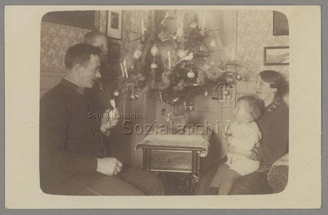 Familie um kleinen, geschmückten Weihnachtsbaum, um 1920