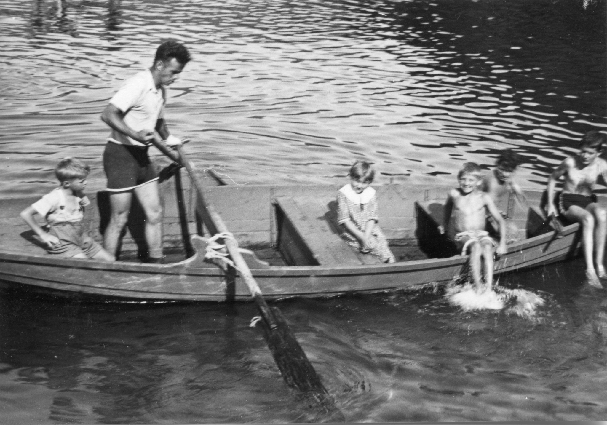 Ein Betreuer fährt mit Kindern Ruderboot