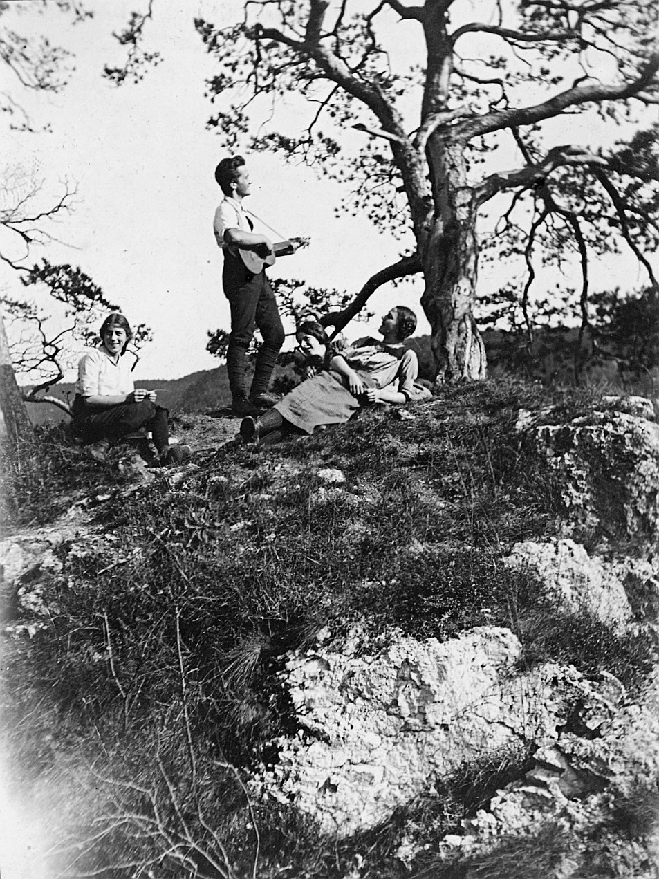 Drei Wandervögel (Frauen) liegen ode sitzen auf der Wiese, ein Junge Gitarre spielend (1915)