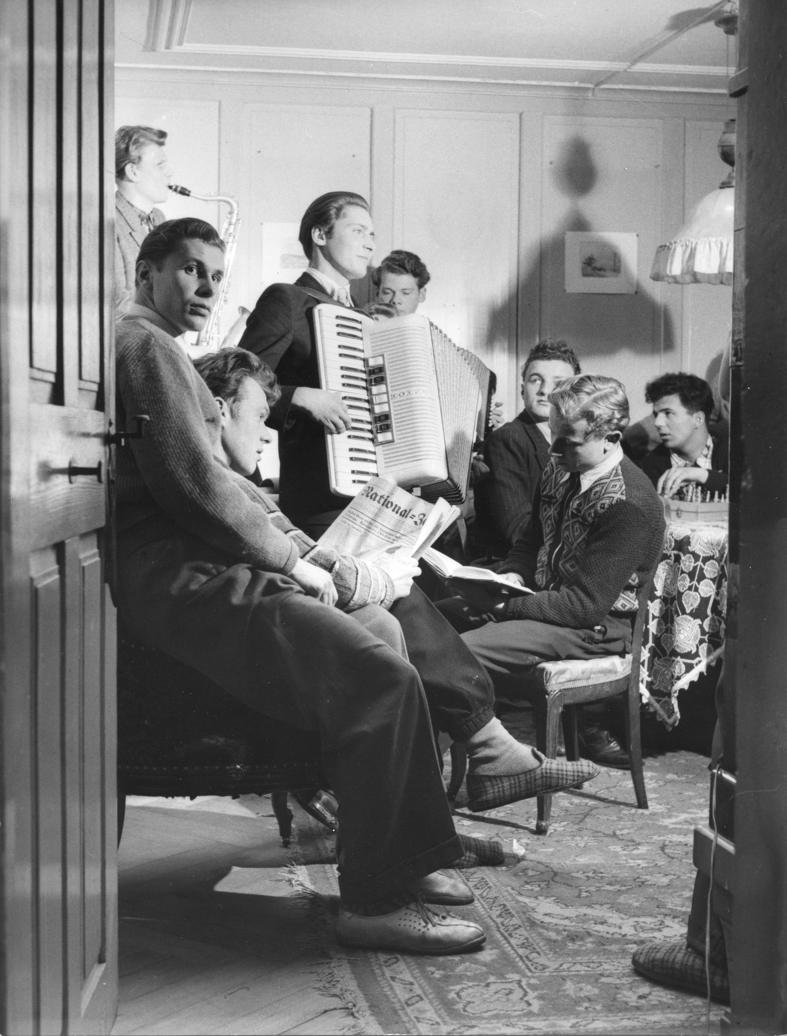 Erholungsaktion für jugendliche deutsche Flüchtlinge im Ferienhaus Lindenbühl 1952/1953; Jugendliche in einer Stube musizierend, lesend und Schach spielend