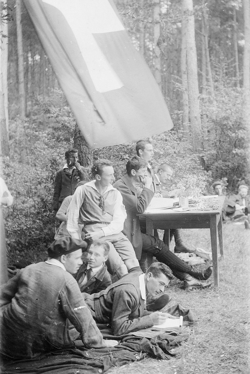 Wandervogel-Landsgemeinde bei Steinmaur (Heitlisberg): Der Bundesvorstandstisch mit acht jungen Männern im Freien - Schweizerfahne a