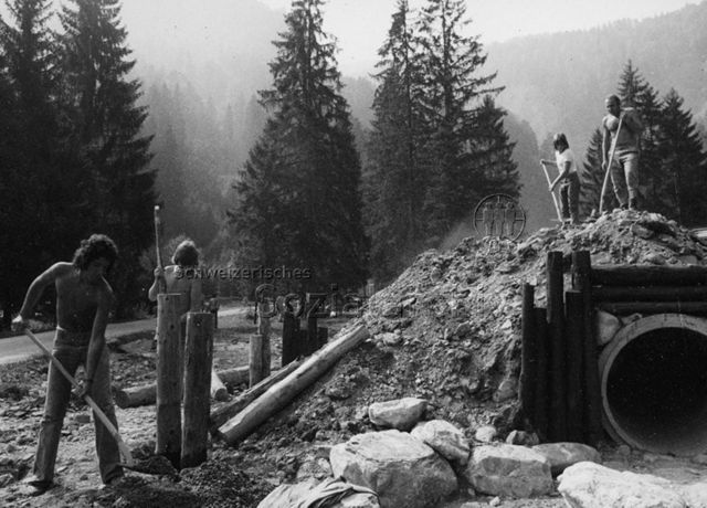 "Fronarbeit für Spielplatz Grüsch" - Jugendliche beim Zuschütten einer Betonröhre; 1973