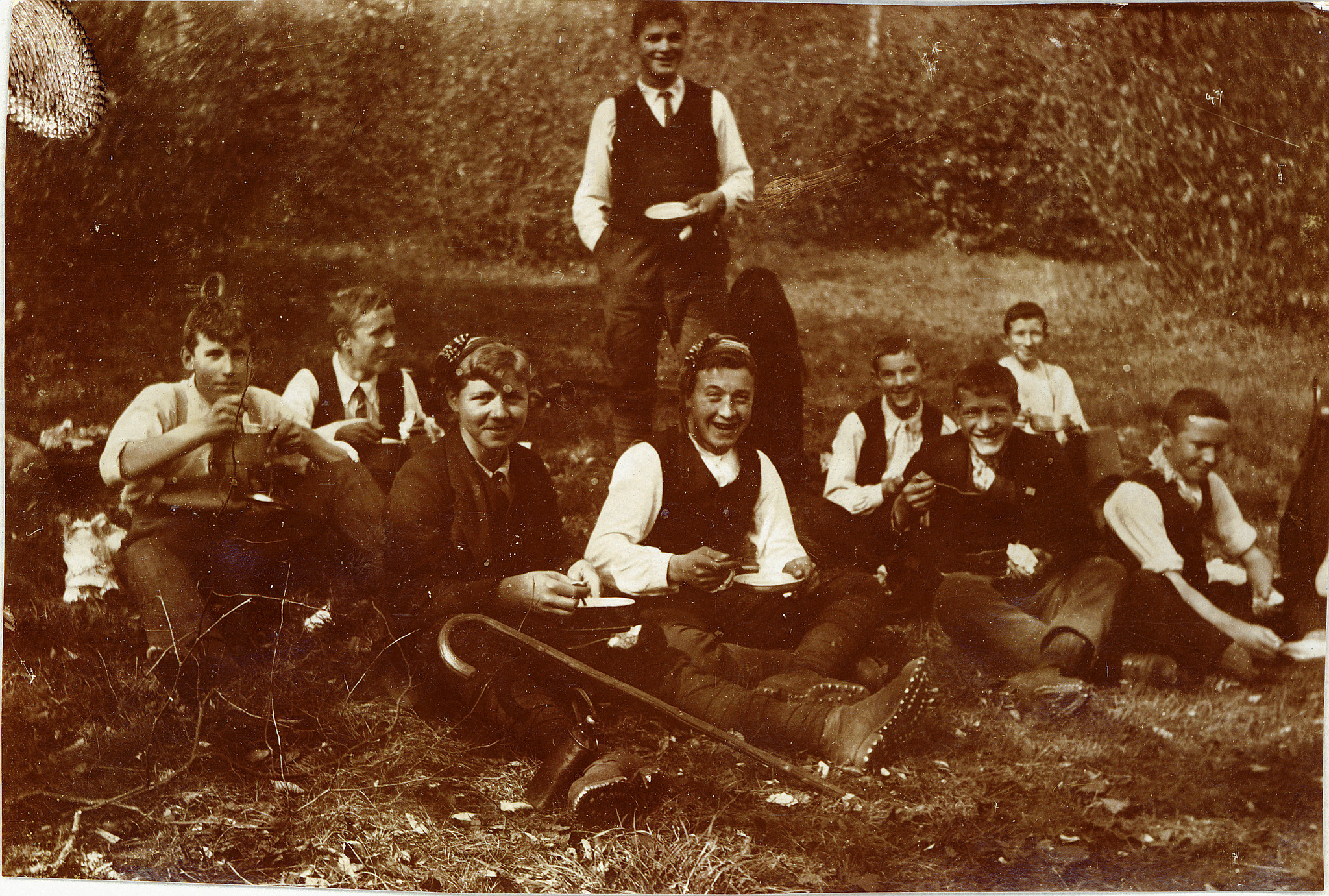 Wandervögel am Westschweizerischen Wandervogeltag in Magglingen sitzen auf der Wiese und essen aus ihren Essnäpfen (1912)